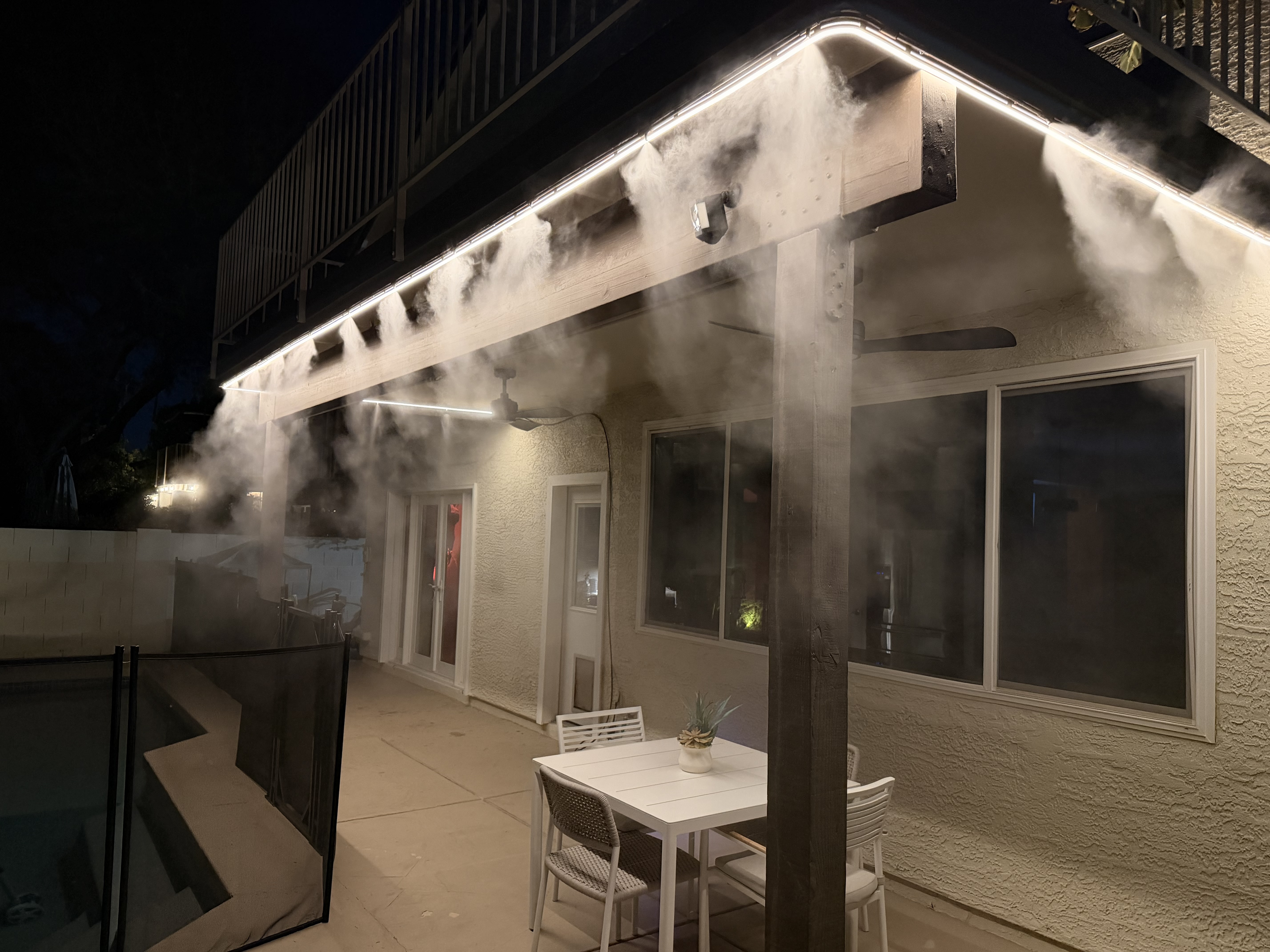 Residential patio with warm white lights and mist at night